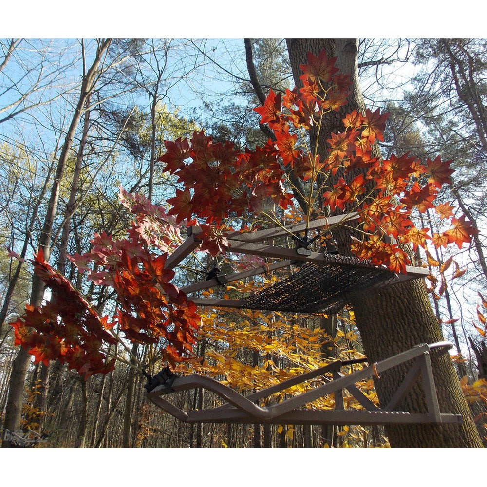 Treestand mounted on a tree in fall woods covered with red and orange artificial maple leaves for camouflage